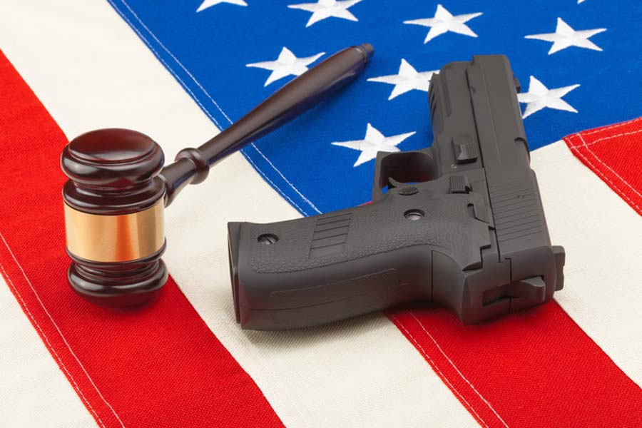 A gavel and a handgun rest on an American flag, symbolizing the intersection of law and gun rights in the United States.