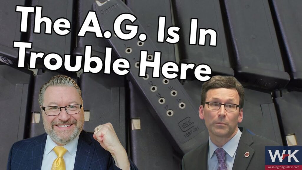 An image featuring two men in front of a backdrop of gun magazines. The man on the left is smiling and raising his fist; the man on the right looks serious. Text reads, "The A.G. Is In Trouble Here." Logos and branding appear in the corners.