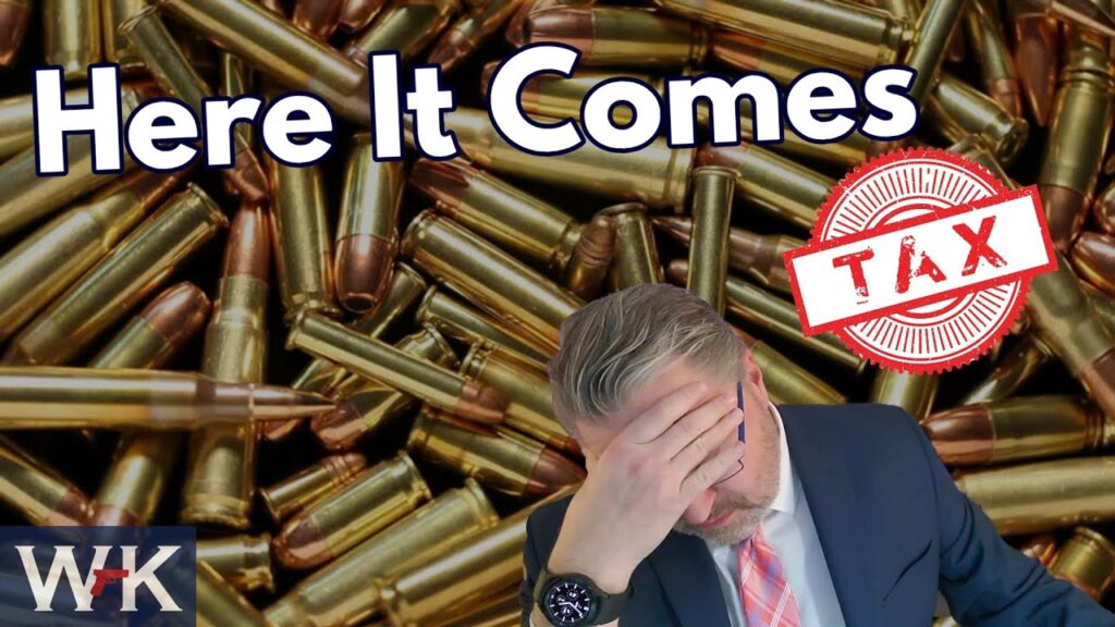 A man holds his head in distress in front of a background of bullet casings, with the text "Here It Comes" and a red stamp that reads "Tax" overlaid. A small "WK" logo is in the bottom left corner.