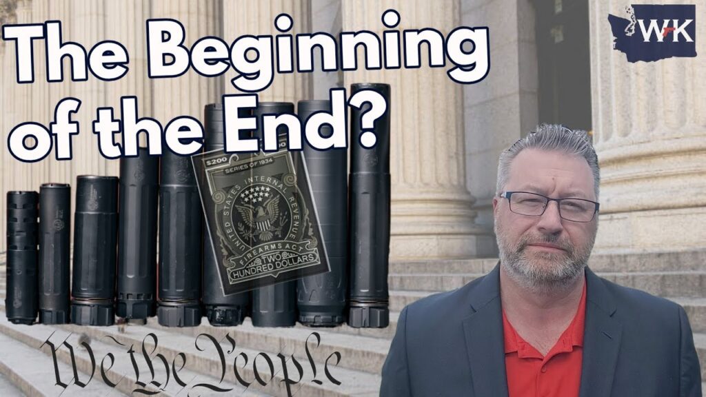 A man in a suit stands in front of a building with large columns. The text "The Beginning of the End?" is displayed above cylindrical objects and a US hundred-dollar bill. The phrase "We the People" is written at the bottom.