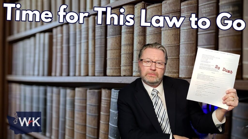 A man in a suit and tie is sitting in front of a bookshelf filled with law books. He is holding a document marked "So Dumb." The text "Time for This Law to Go" is written above him.