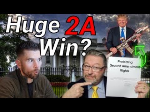 Two men in the foreground, one pointing at a document labeled "Protecting Second Amendment Rights." Text reads "Huge 2A Win?" A small image of a man with a guitar is in the background near a building resembling the White House.