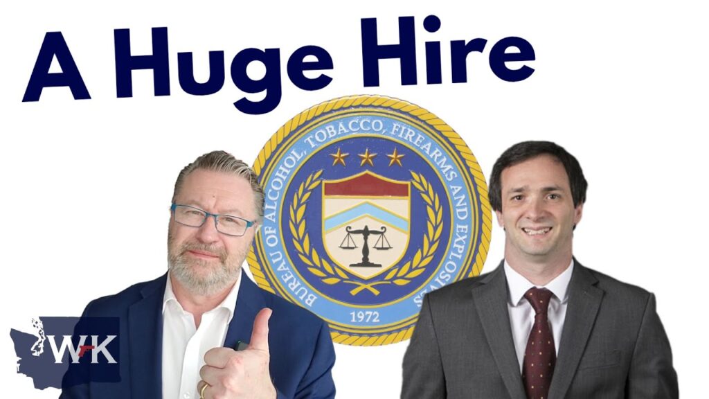 Two men in suits stand in front of the Bureau of Alcohol, Tobacco, Firearms and Explosives emblem. One man gives a thumbs-up. The text "A Huge Hire" is at the top left.