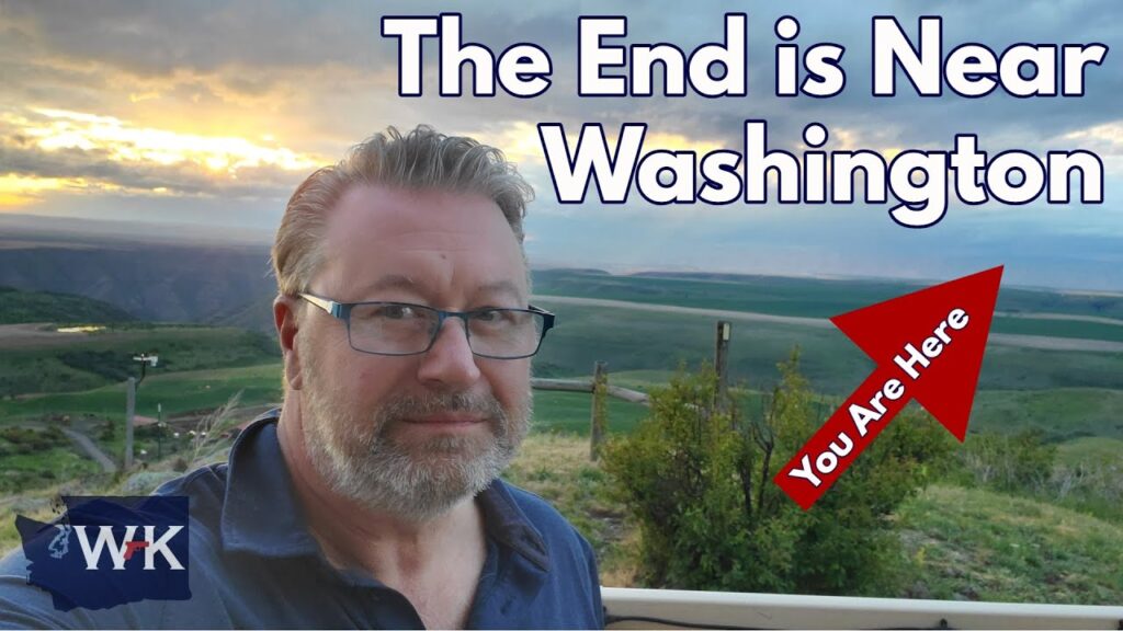 A man with glasses and a beard stands outdoors with green hills and a cloudy sunset in the background. Large text reads, "The End is Near Washington." A red arrow says, "You Are Here.