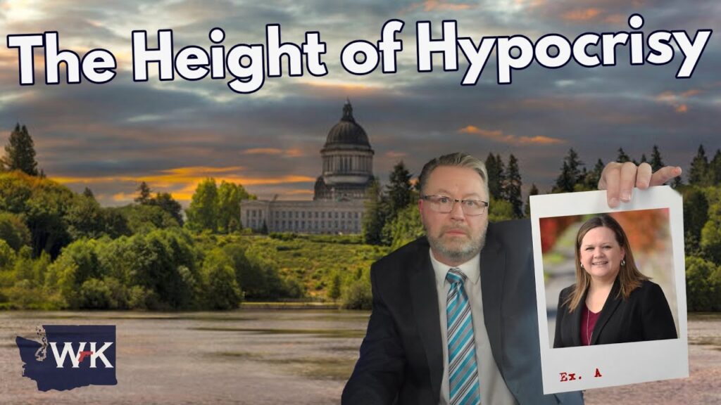 A man in a suit holds up a photo of a smiling woman; behind him is a scenic view of a government building with trees and water. Large text reads, "The Height of Hypocrisy.