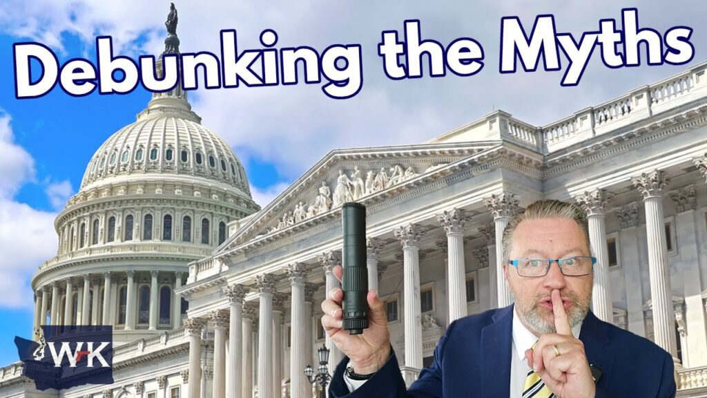 A man in a suit holds a flashlight and gestures "shh" in front of the U.S. Capitol building. Text reads "Debunking the Myths" with a small "WK" logo in the bottom left corner. The sky is blue with some clouds.