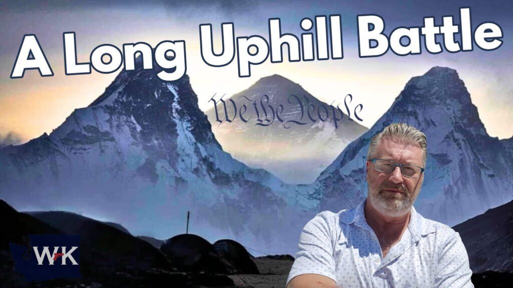 A man with glasses and a trimmed beard stands in front of snowy mountains with "A Long Uphill Battle" and "We the People" written in the sky. The WK logo is in the lower left corner.