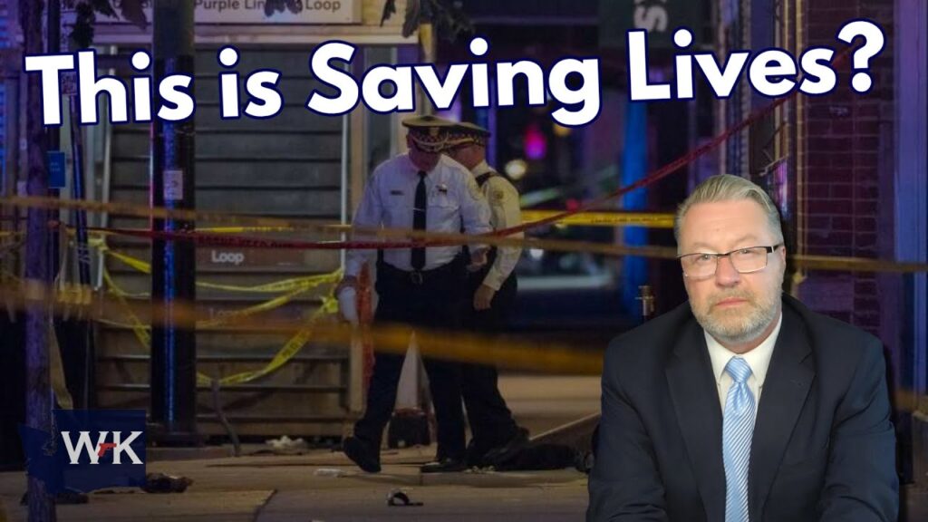 Two police officers stand behind yellow crime scene tape at night. Large text reads, "This is Saving Lives?" A serious-looking man in a suit appears in the corner, and the "WK" logo is in the bottom left.