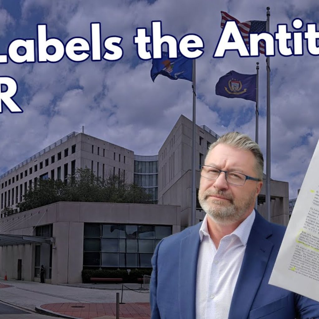 A man in a suit holds up a document in front of a federal building with flags. The text on the image reads, "ATF Labels the Antithesis a SBR." The WTK logo is in the lower left corner.