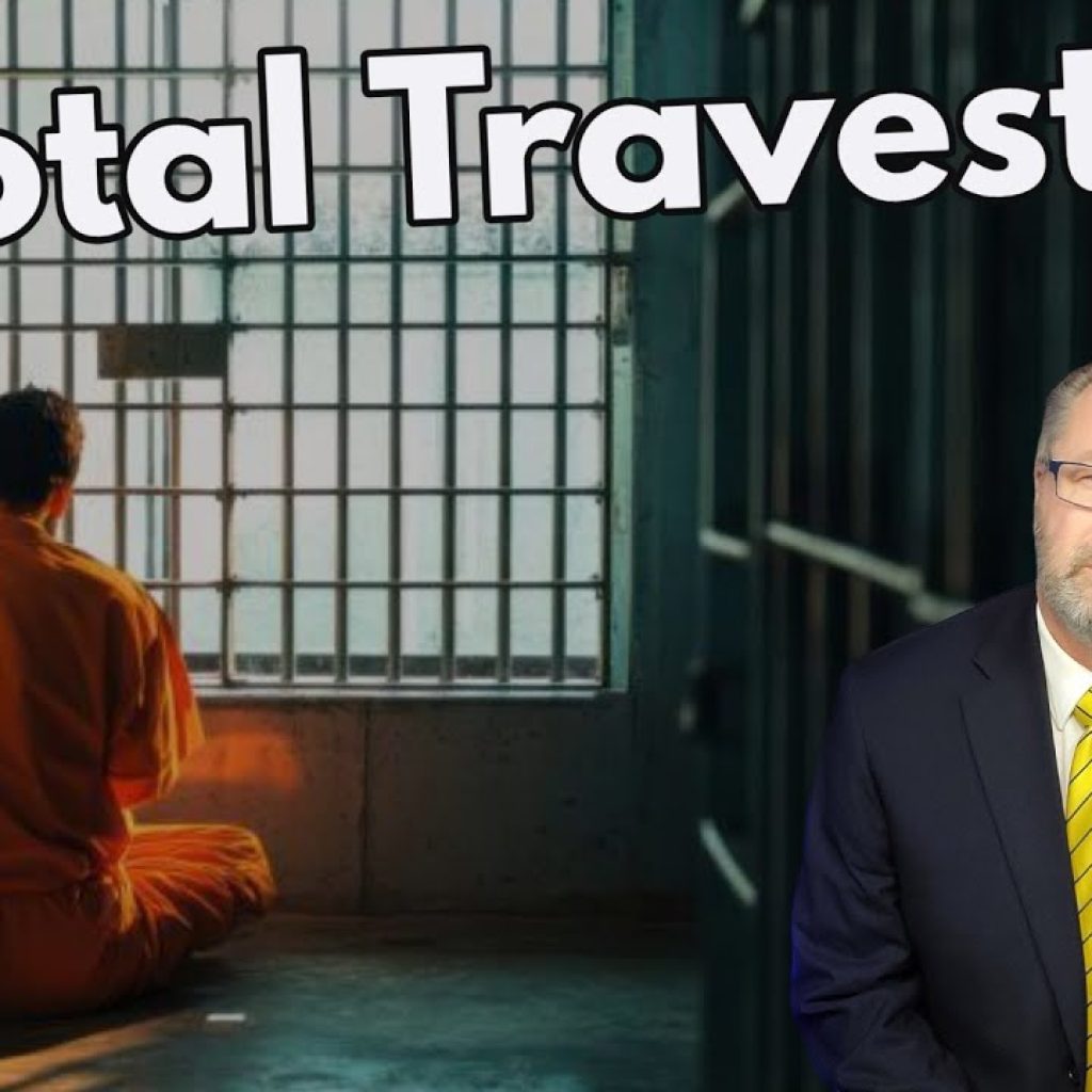 A man in an orange prison uniform sits on a bed in a jail cell. The text “A Total Travesty” appears above. In the foreground, a man in a suit and yellow tie looks at the camera. The WK logo is in the corner.